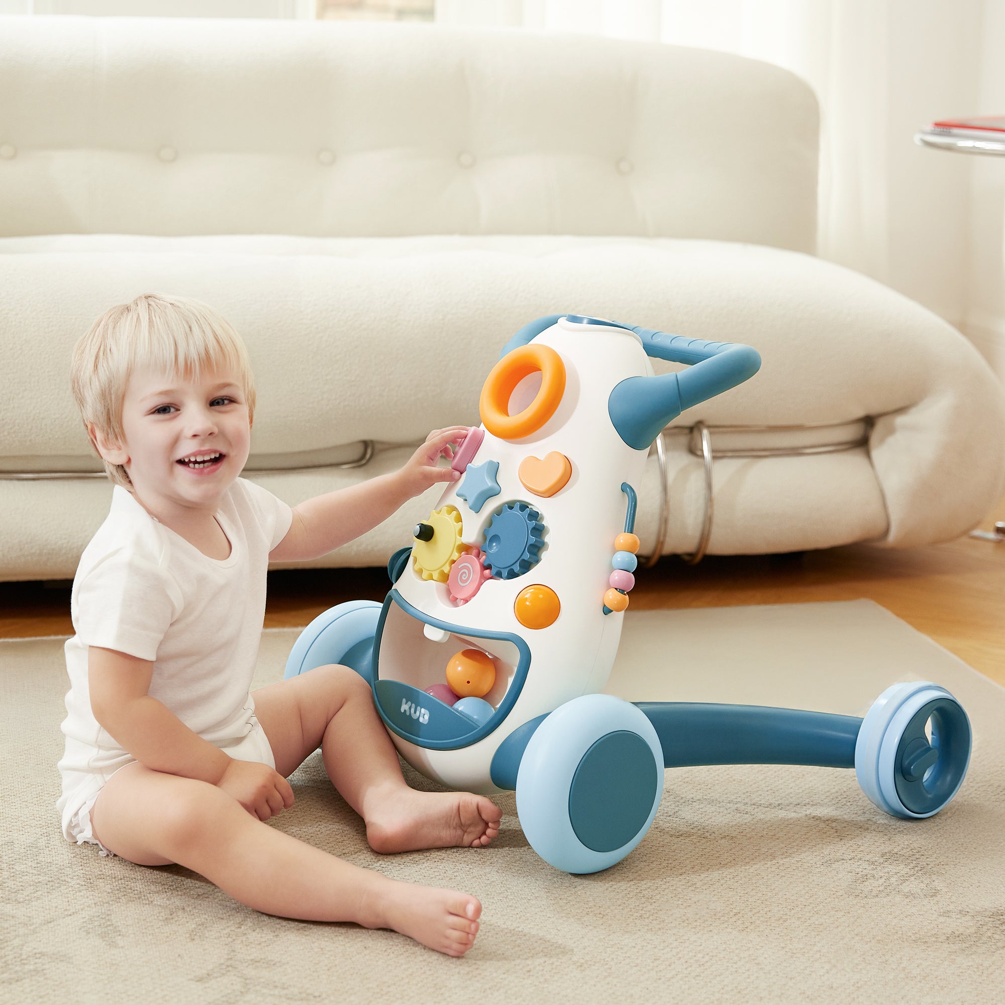 Little boy sitting in front of blue KUB baby walker and playing